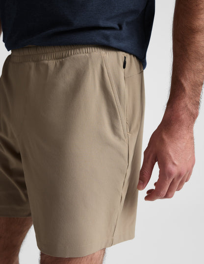 Close-up of beige Pivotal 2.0 Men's Lined Short 7" showing the side pocket, elastic waist, and hidden zipper detail.