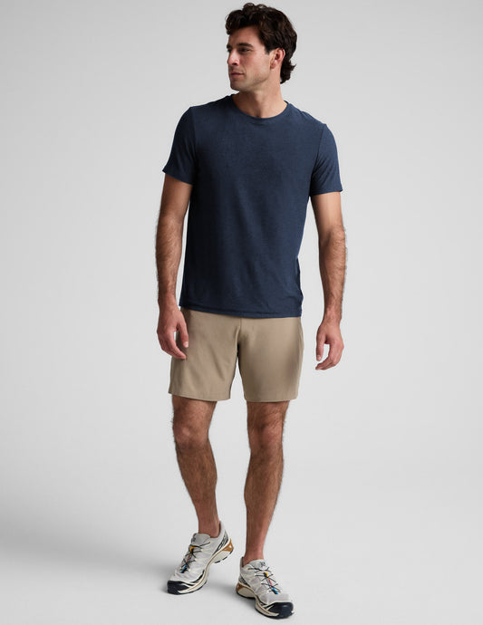 Man wearing beige Pivotal 2.0 Men's Lined Short 7" with blue t-shirt. Features a relaxed fit and 7-inch inseam.