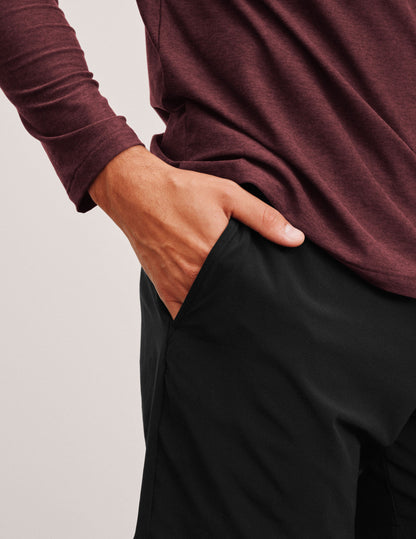 Detail of a hand in the pocket of the black Pivotal 2.0 Men's Short 7", paired with a maroon long-sleeved shirt.