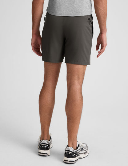 Back view of a man wearing Pivotal 2.0 Men's Short 7" in dark gray with an elastic waistband and zippered back pocket.