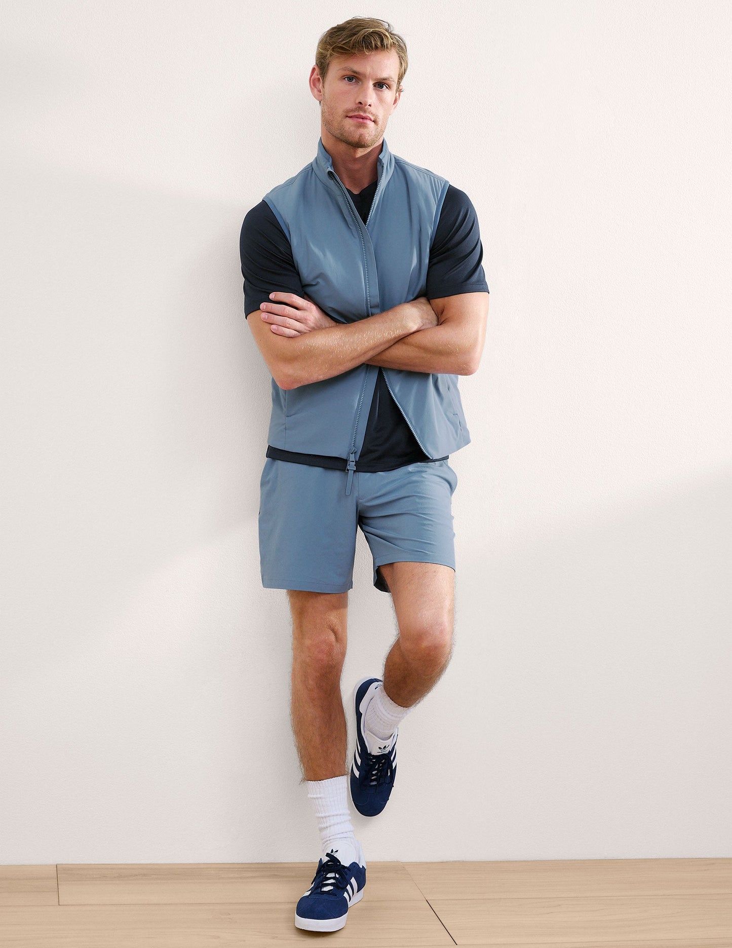 Man wearing Navy Pivotal 2.0 Men's Short 7"™ paired with a blue vest, black t-shirt, and white socks.