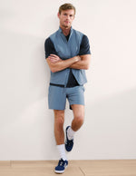Man wearing Navy Pivotal 2.0 Men's Short 7"™ paired with a blue vest, black t-shirt, and white socks.