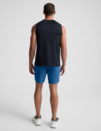 Man wearing Blue Pivotal 2.0 Men's Short 7™ from a rear view, paired with a black sleeveless top and white sneakers.
