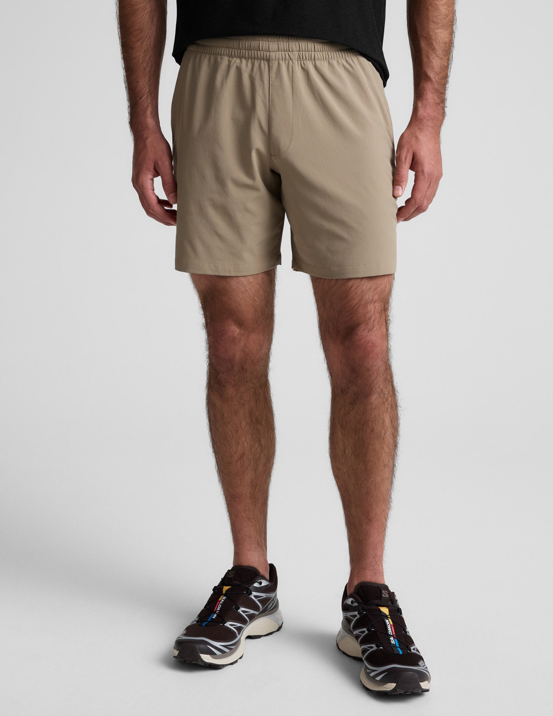 Front view of the beige Pivotal 2.0 Men's Short 7" featuring a gathered elastic waistband and relaxed mid-thigh fit.