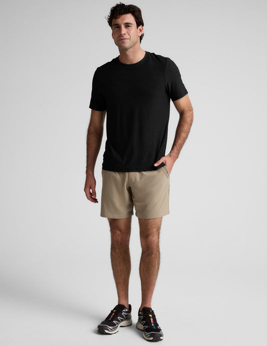 Man standing in beige Pivotal 2.0 Men's Short 7" and a black t-shirt. Front view of relaxed fit, mid-thigh shorts.