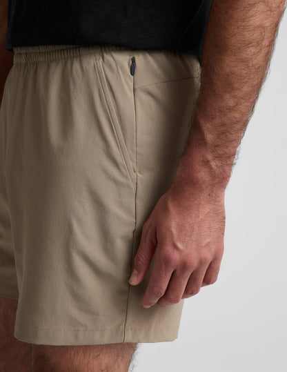 Side detail of beige Pivotal 2.0 Men's Short 7" featuring an elastic waistband and a hidden side zipper pocket.