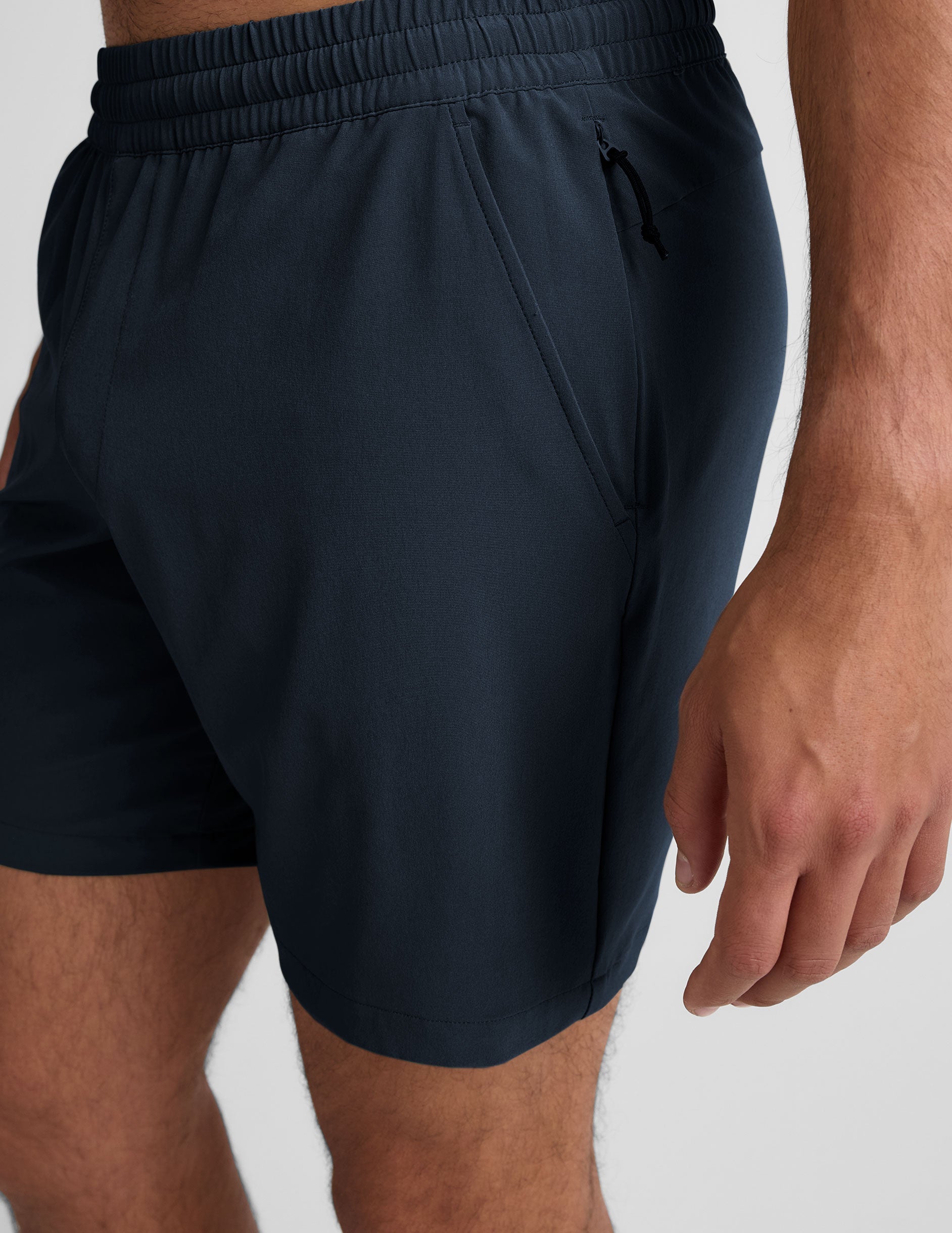 Side view of navy Pivotal 2.0 Men's Short 7" with an elastic waistband and zippered side pocket on a model.