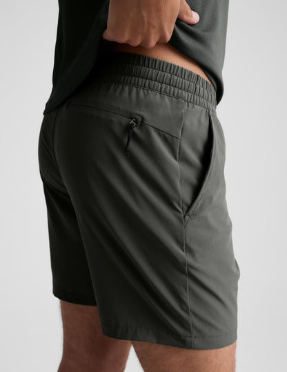 Rear view of man wearing Olive Pivotal 2.0™ Men's Short 7" with a grey shirt, featuring a back yoke invisible zip pocket.
