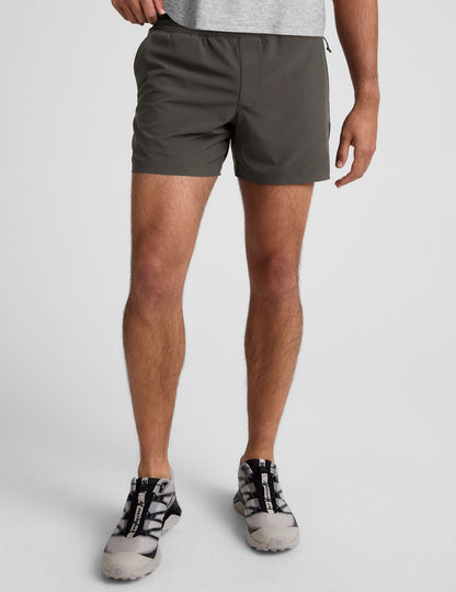 Front view of a man wearing the dark gray Pivotal 2.0 Men's Lined Short 5" with an elastic waistband and relaxed fit.