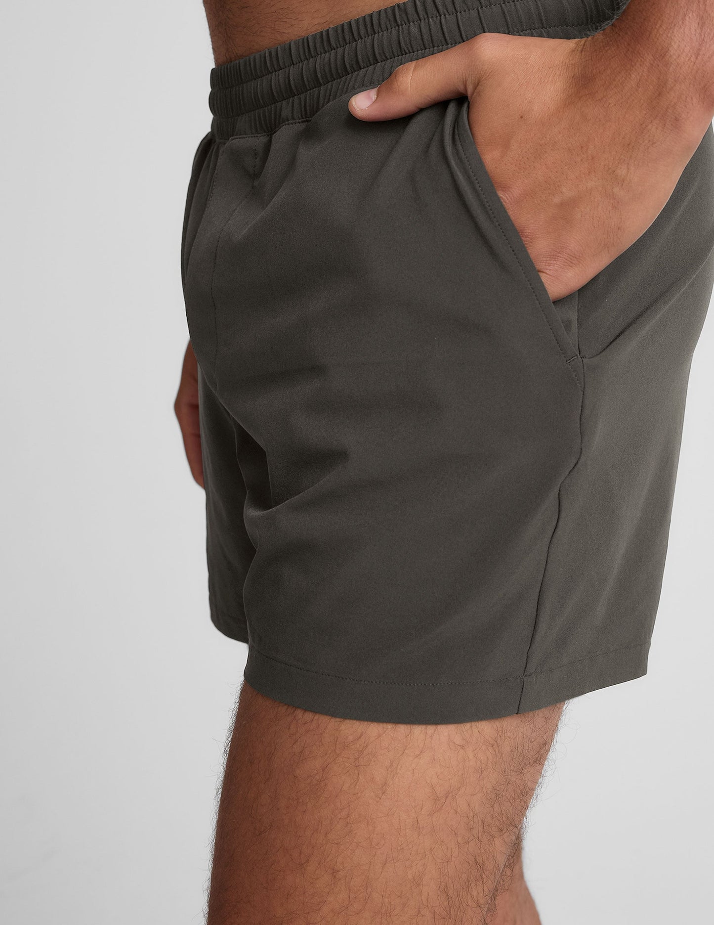 Side view of gray Pivotal 2.0 Men's Lined Short 5" showing the elastic waistband and hand resting in the side pocket.