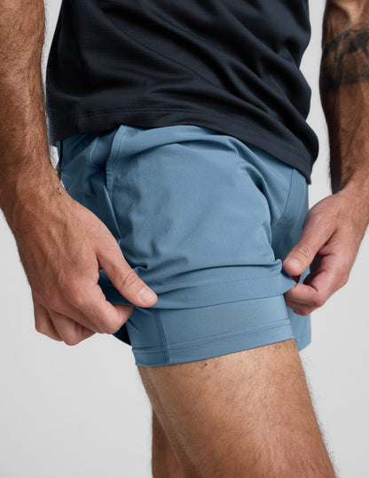 Blue Pivotal 2.0 Men's Lined Short 5" shown in a close-up with the hem lifted to display the matching built-in liner.