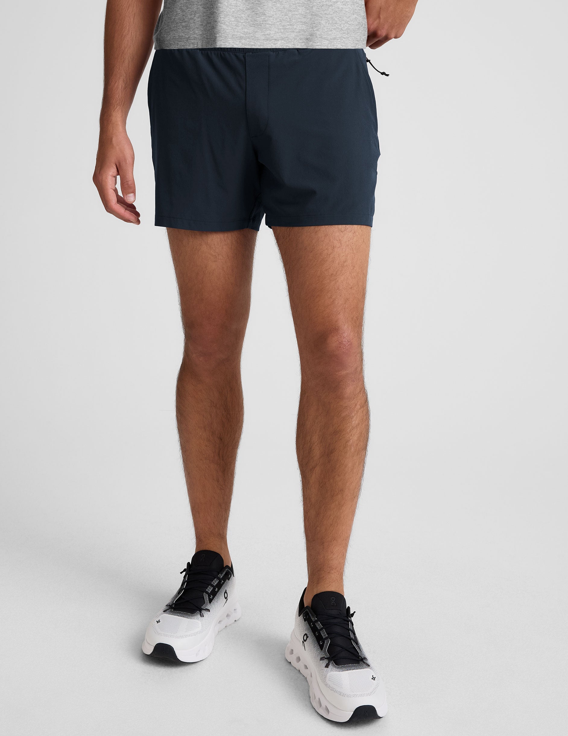 A model wears navy Pivotal 2.0 Men's Lined Shorts with a 5" inseam and elastic waistband, hitting at the mid-thigh.