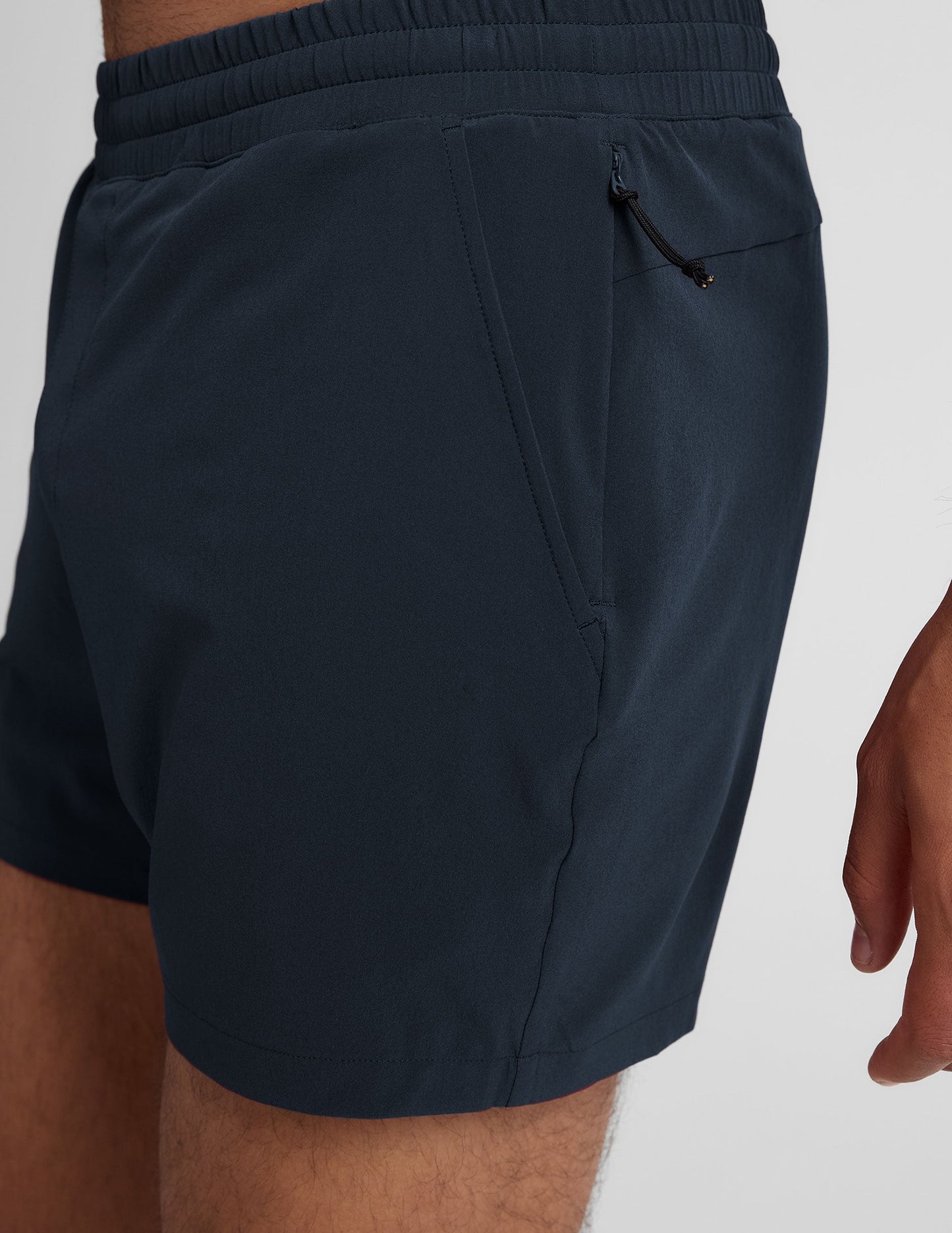 Side view of navy Pivotal 2.0 Men's Lined Short 5" featuring an elastic waistband, side pocket, and zipper closure detail.