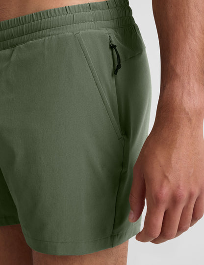 Side view of olive Pivotal 2.0 Men's Lined Short 5" on a person, showing the elastic waistband and side zipper pocket.