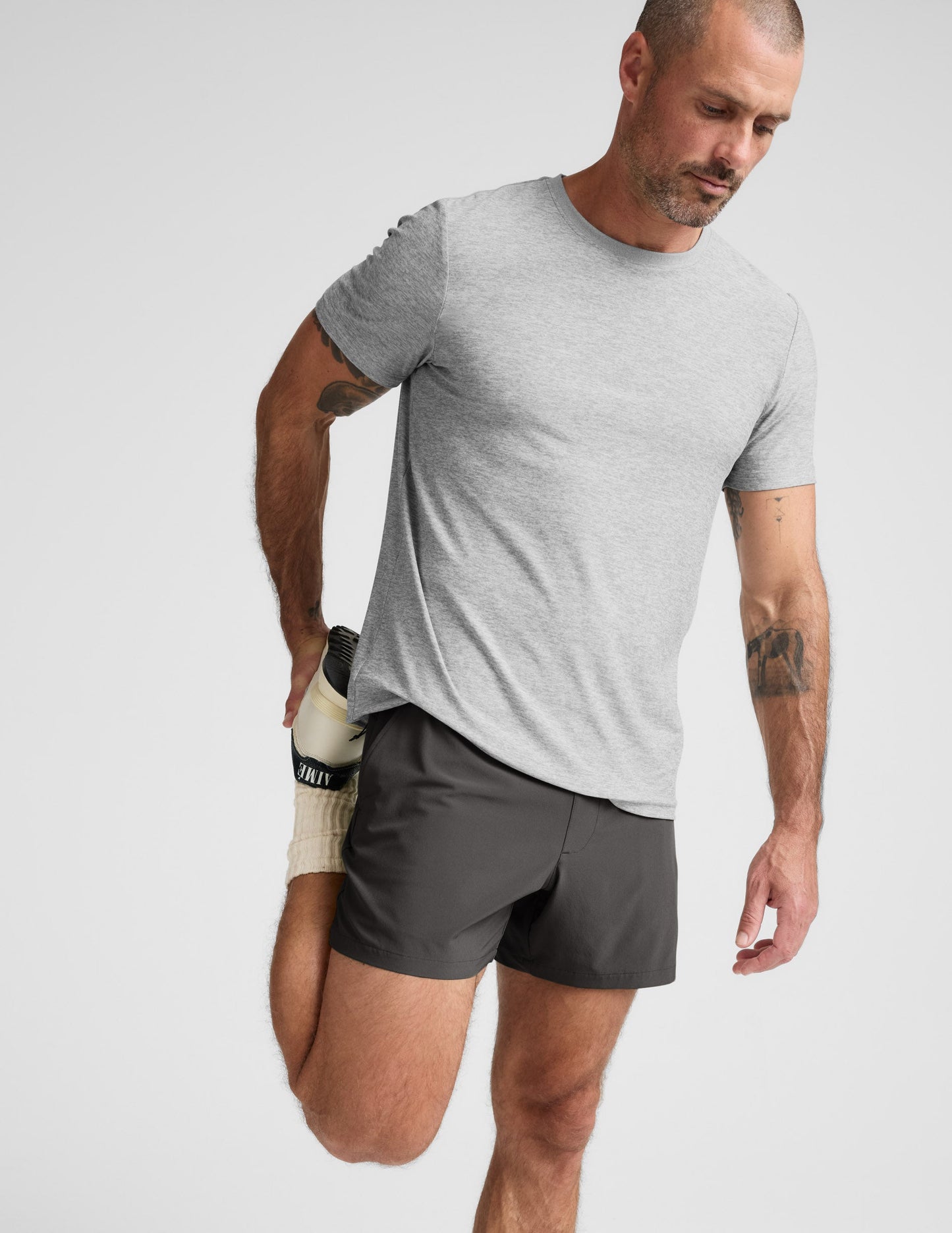 Man wearing a gray t-shirt and shorts on a light gray background.