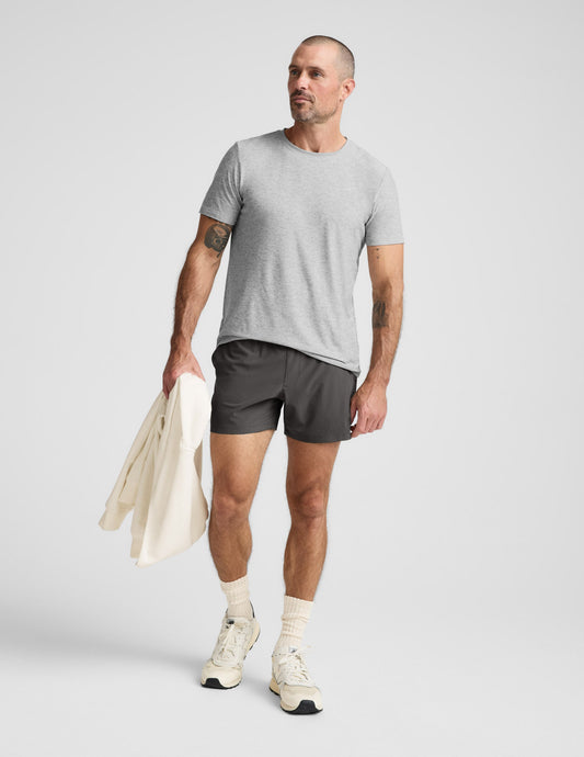 Man wearing a gray t-shirt and shorts on a light gray background.