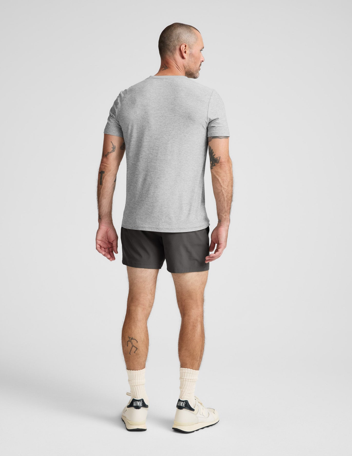 Man wearing a gray t-shirt and shorts on a light gray background.