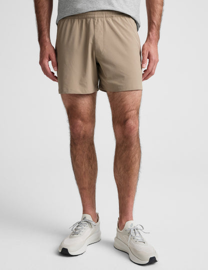 Front view of Pivotal 2.0 Men's Short 5" in beige, featuring a relaxed mid-thigh fit and a gathered elastic waistband.