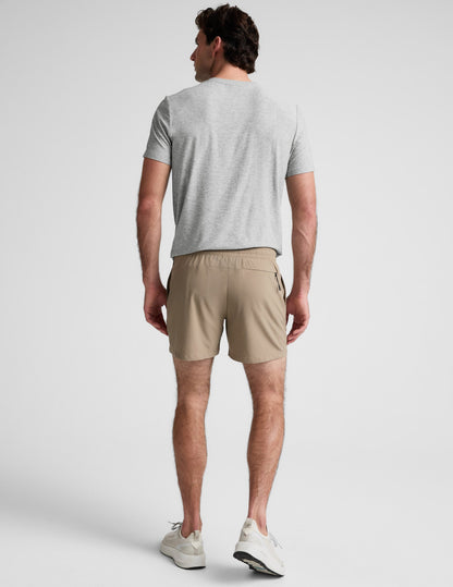 Rear view of beige Pivotal 2.0 Men's Short 5" featuring an elastic waistband and back zipper pocket on a male model.