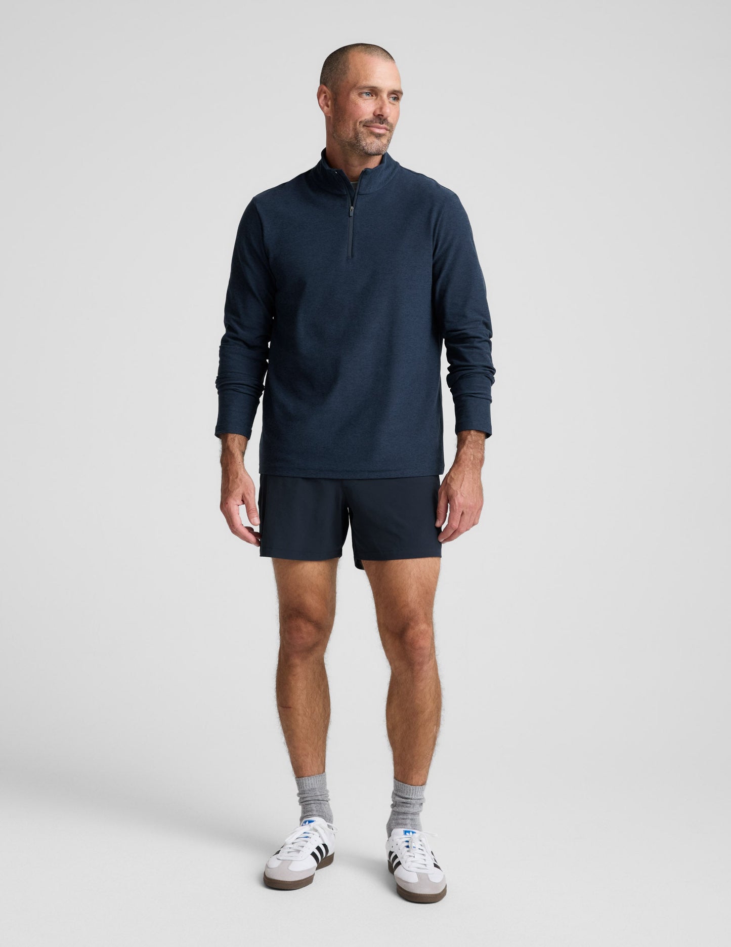 Man wearing a navy long-sleeve shirt and shorts on a white background.