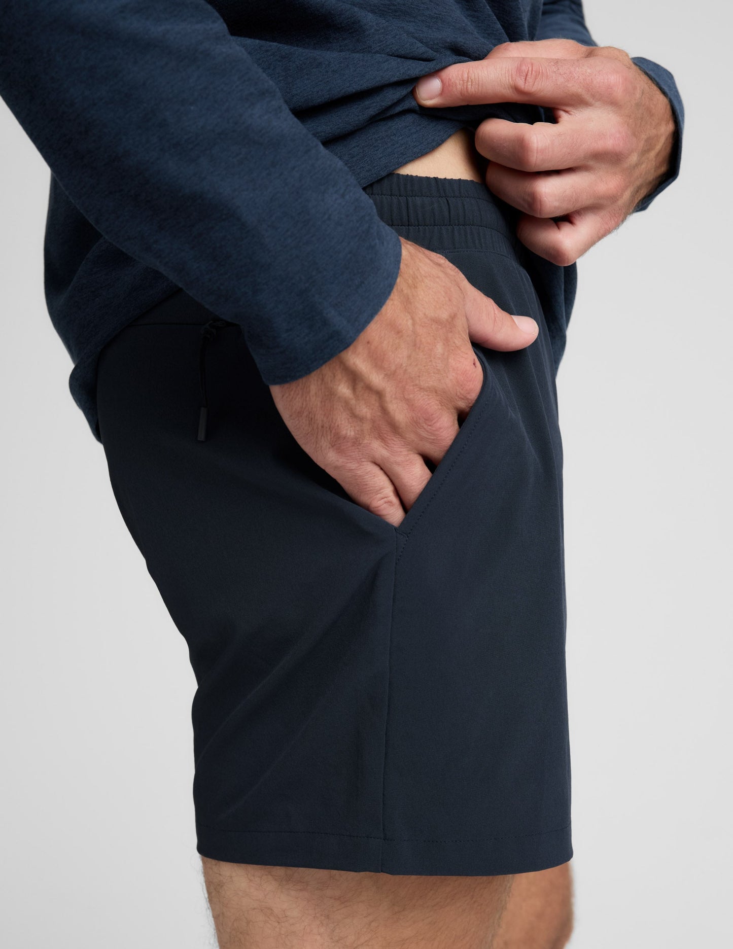 Man wearing a navy long-sleeve shirt and shorts on a white background.