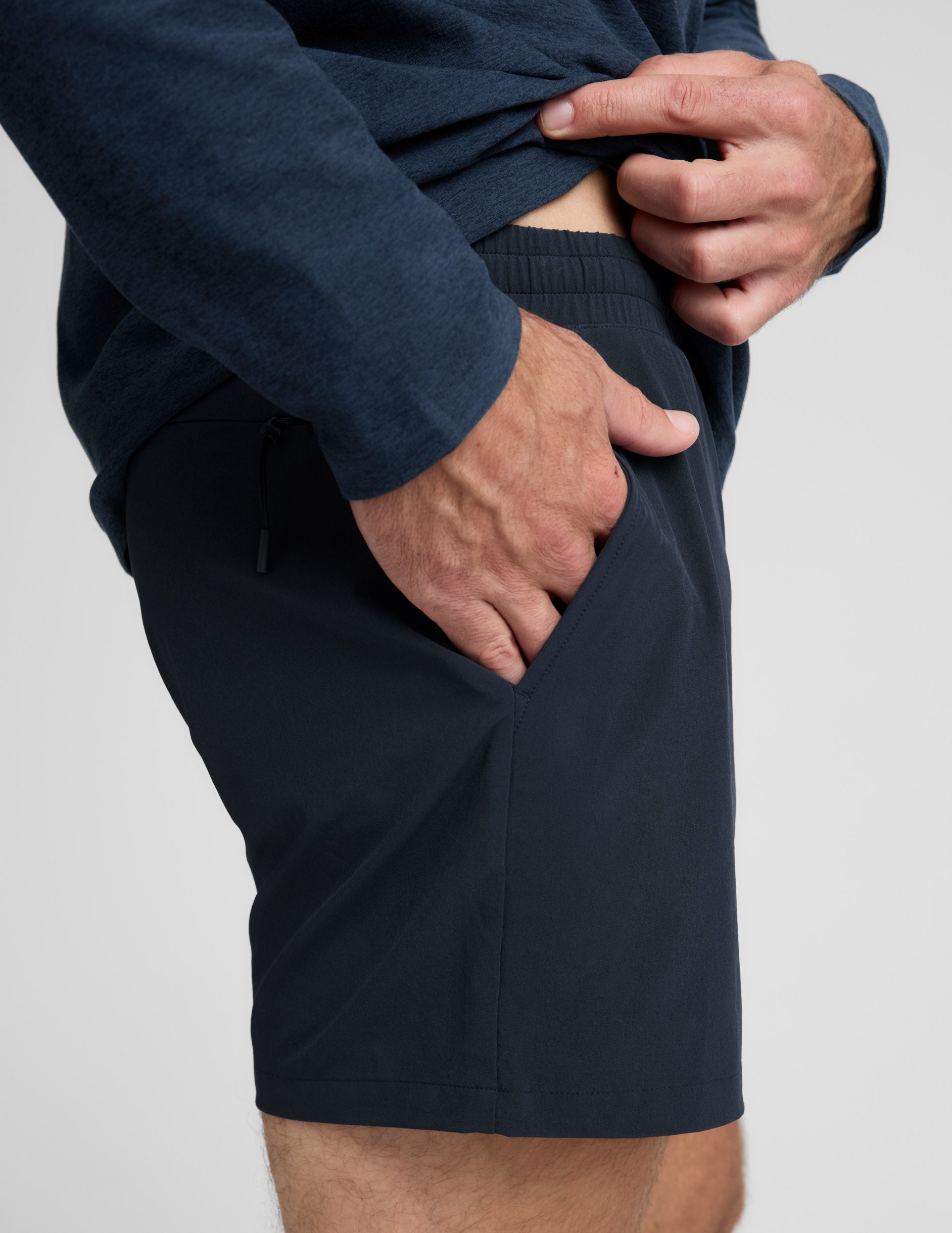 Man wearing a navy long-sleeve shirt and shorts on a white background.