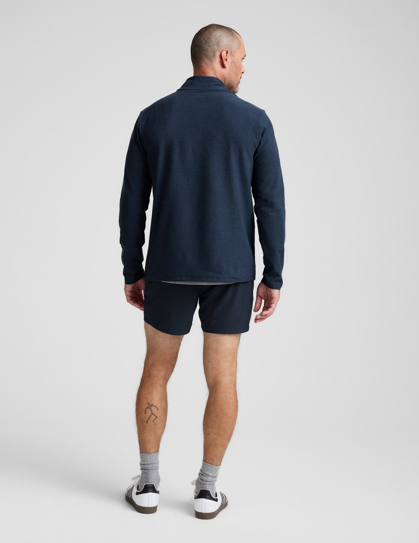 Man wearing a navy long-sleeve shirt and shorts on a white background.