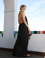 Woman in a black dress standing against a tiled wall with colorful border.