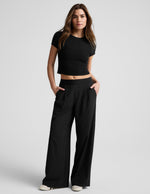 Model in black Elasticated Trouser Pant 29" featuring a wide-leg silhouette, pleated front, and elasticated waistband.