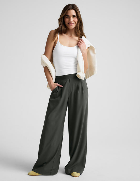 A woman wearing the wide-leg, dark green Elasticated Trouser Pant with front pleats and a comfortable elastic waistband.