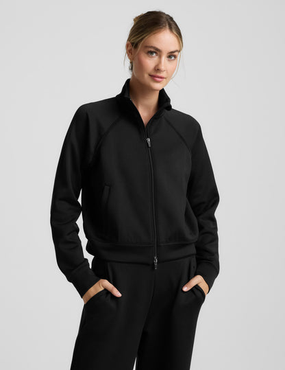 Woman wearing a black tracksuit on a light gray background.
