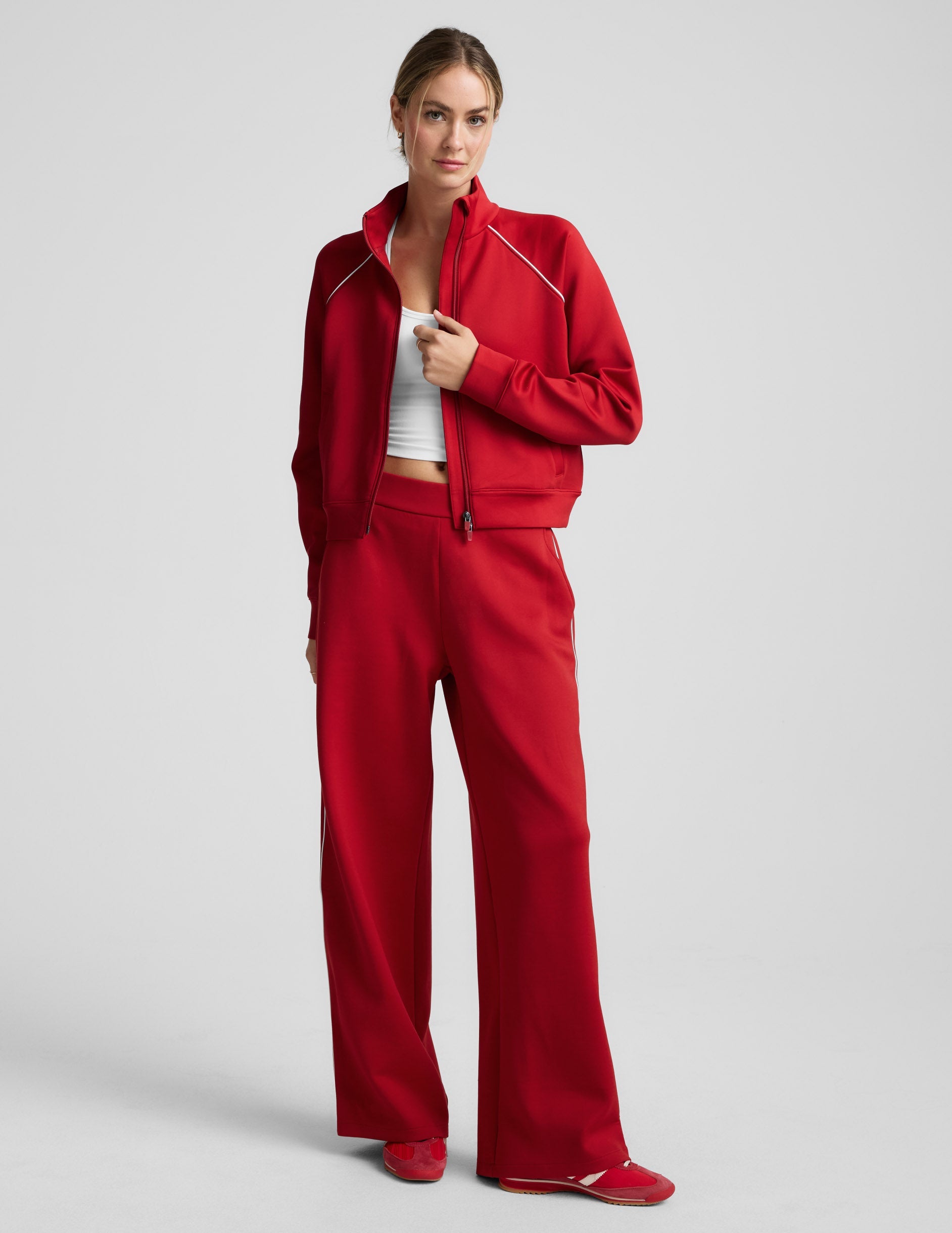 Woman wearing a red jacket with white piping against a plain background.
