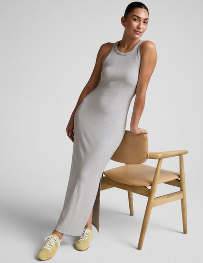 Woman wearing a gray high neck ribbed maxi dress against a plain background.