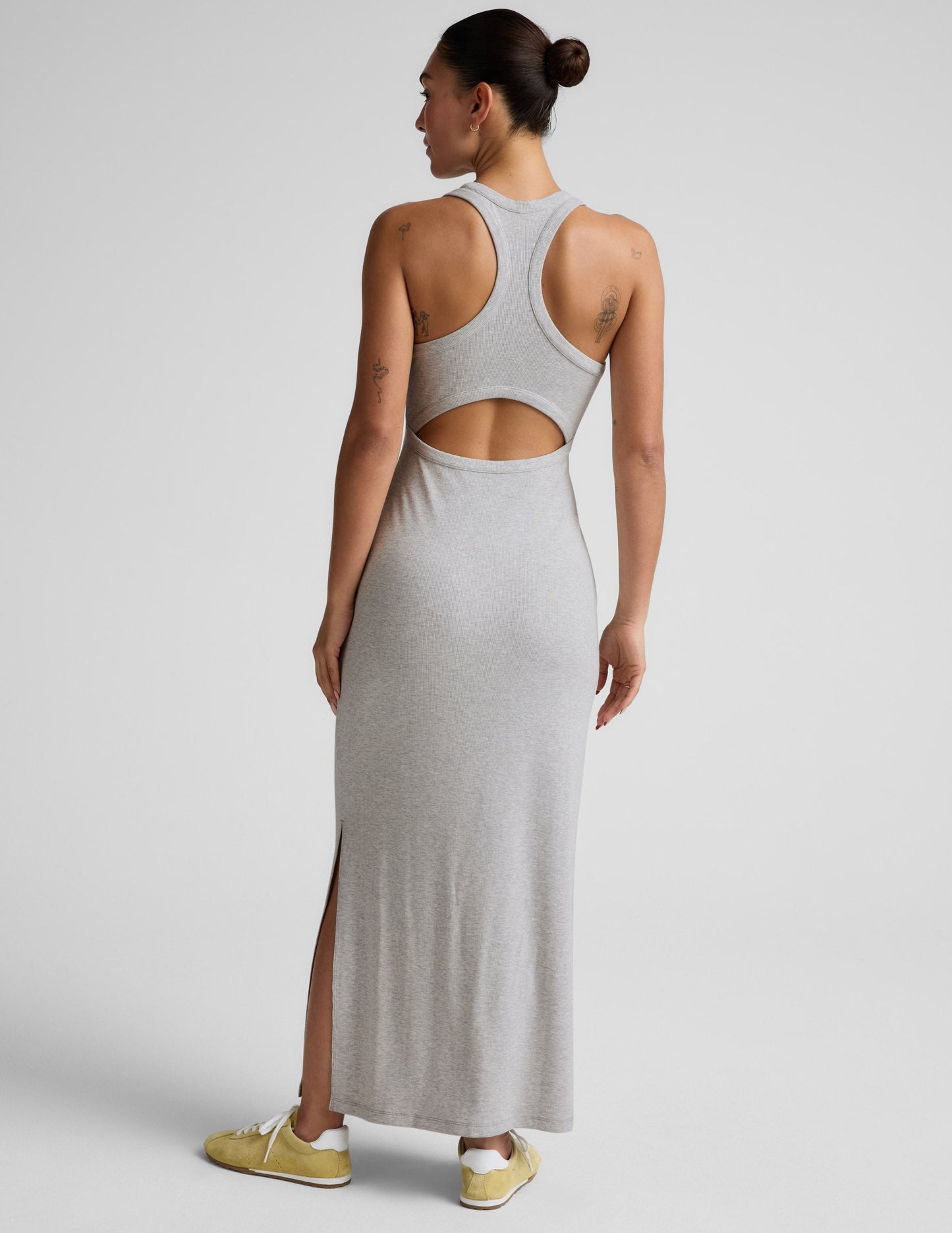Woman wearing a gray high neck ribbed maxi dress against a plain background.