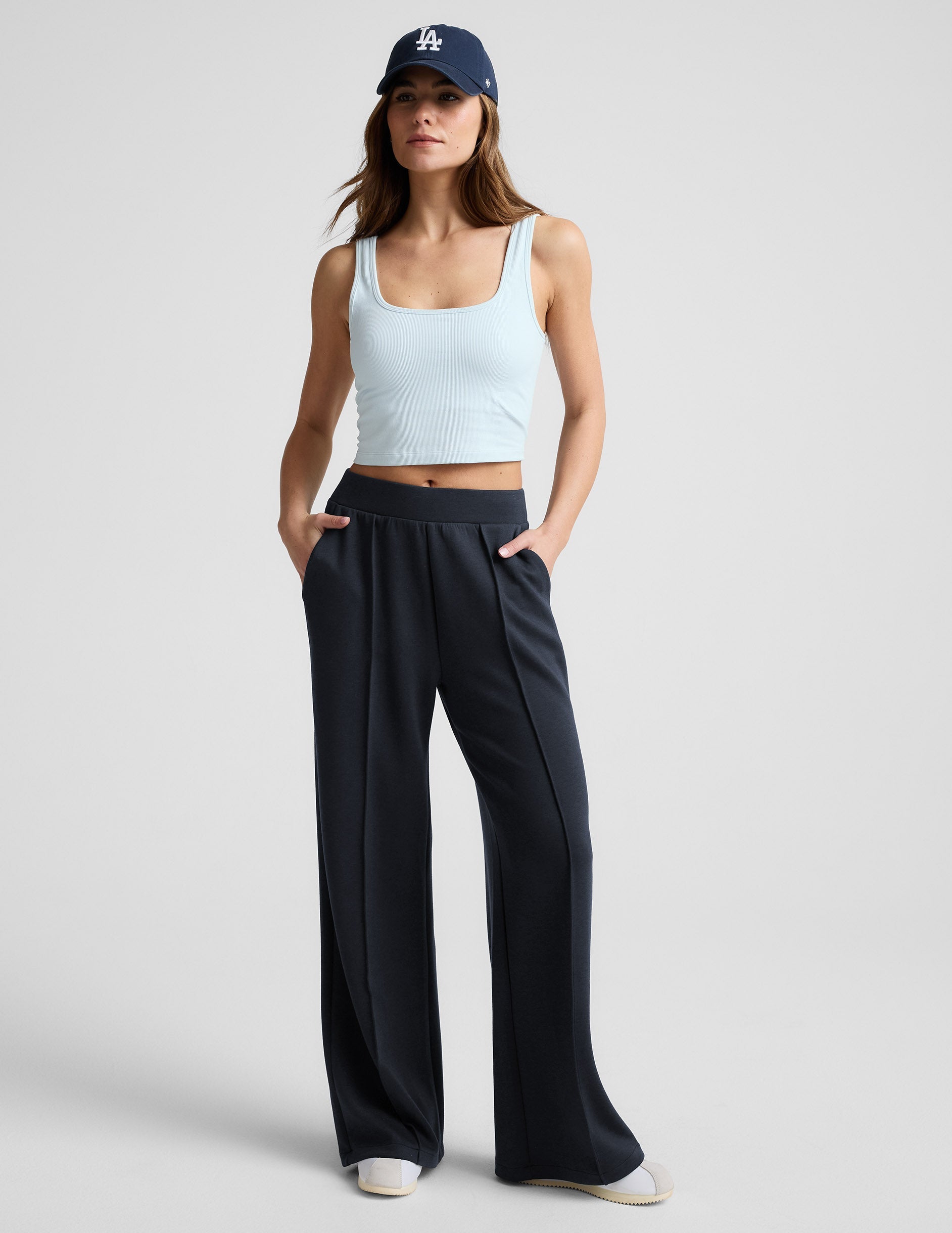 Woman wearing a blue cropped tank and blue pants against a plain background.