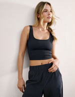 Woman wearing a blue cropped tank and blue pants against a plain background.