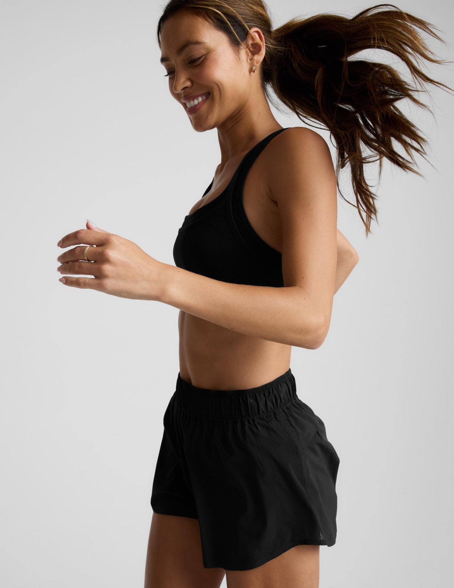 Woman running in black Solemate 2.5" Short with side mesh panels and elastic waistband in a side-profile view.