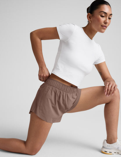Brown Solemate 2.5" Short on a lunging model, featuring a gathered elastic waistband and perforated side panels.
