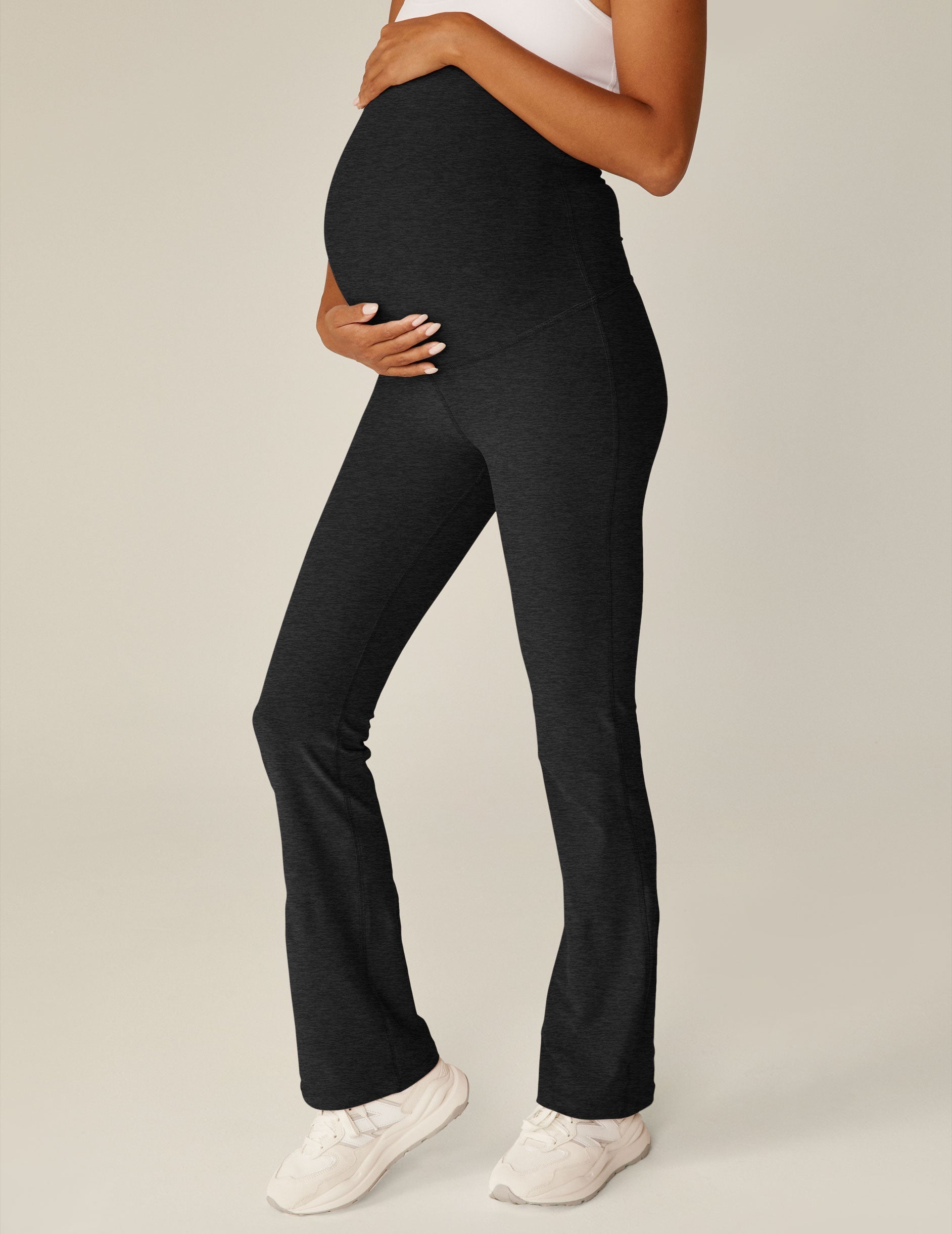 Side view of a pregnant person wearing black marled Spacedye Practice Maternity Pants with a high waist and flare leg.