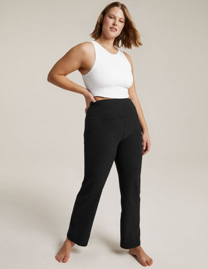 Woman models black marled Spacedye Practice High Waisted Pant with a white crop top, high-rise fit and bootcut leg.