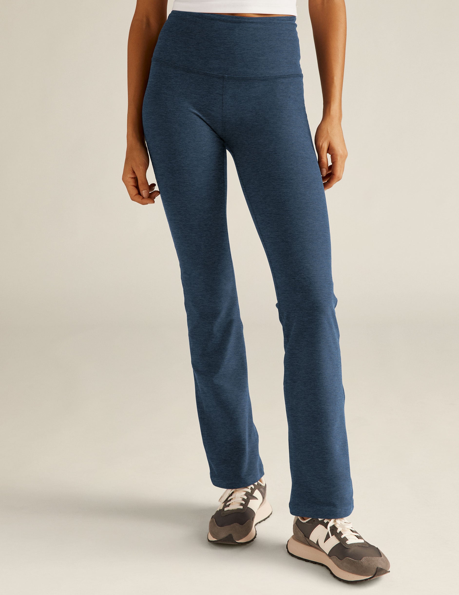 Model in navy Spacedye Practice High Waisted Pants. The marled, bootcut activewear features a wide waistband and snug fit.