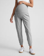 Woman wearing Gray Spacedye Beyond the Bump Maternity Midi Jogger with a white top and white sneakers.