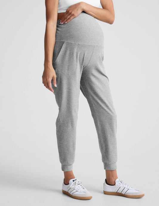 Woman wearing Gray Spacedye Beyond the Bump Maternity Midi Jogger™ with a white tank top and white sneakers.
