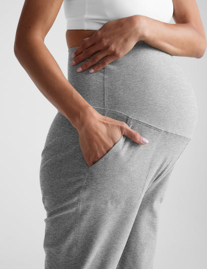 Side profile of Woman wearing Gray Spacedye Beyond the Bump Maternity Midi Jogger™ with a white top, hand in side pocket.