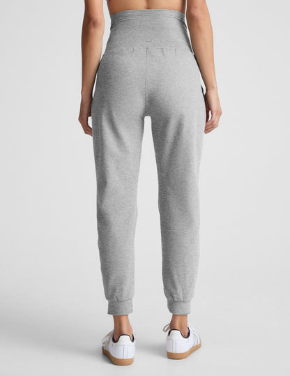 Rear view of woman wearing Gray Spacedye Beyond the Bump Maternity Midi Jogger™ paired with white sneakers.