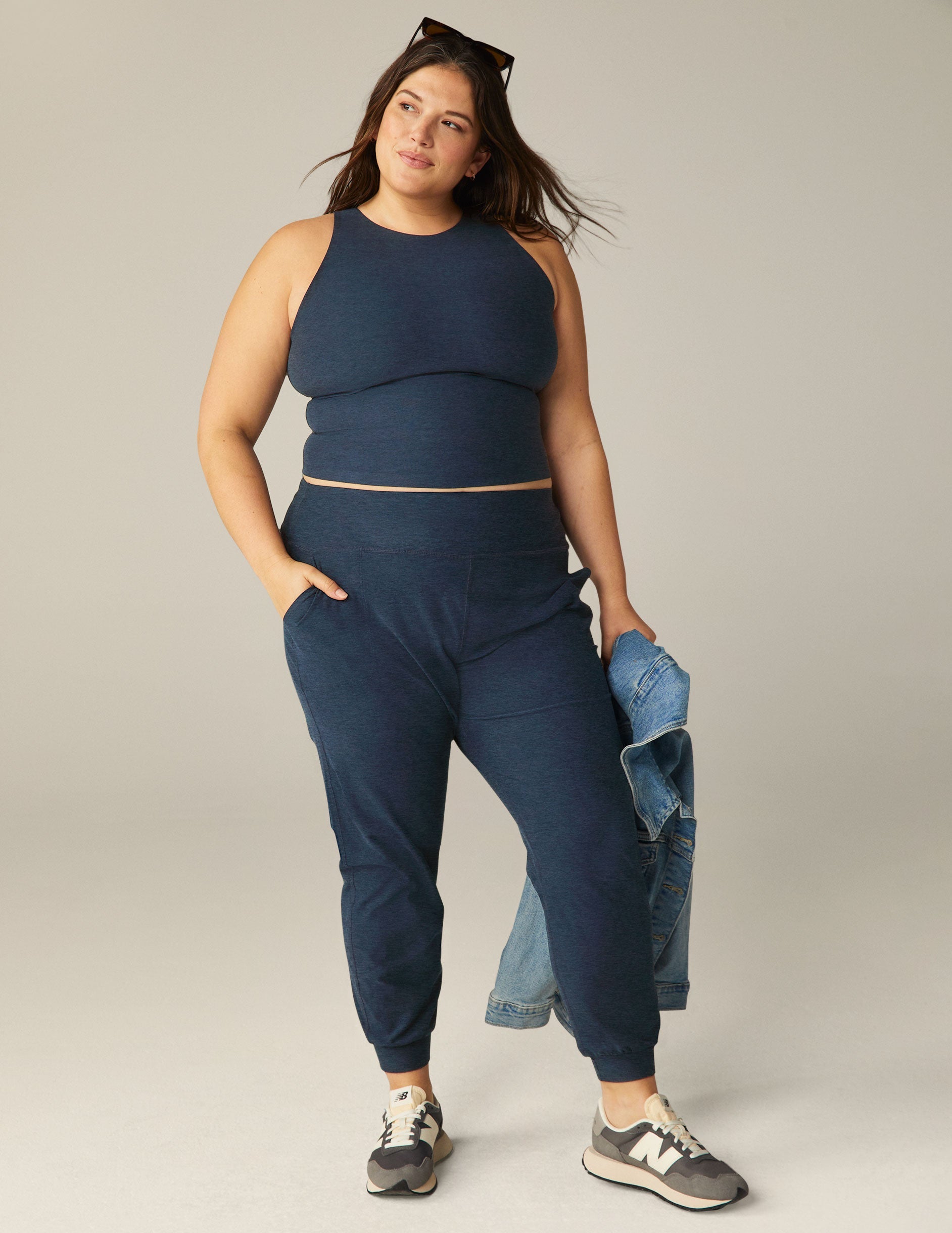 A woman wears the Spacedye Midi Jogger in Nocturnal Navy with a matching tank, side pockets, and cuffed ankles.