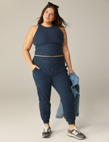 A woman wears the Spacedye Midi Jogger in Nocturnal Navy with a matching tank, side pockets, and cuffed ankles.