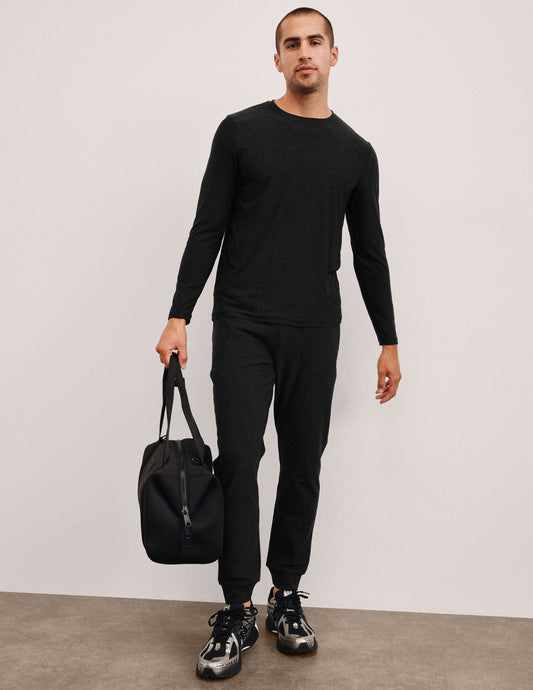 Man wearing black Spacedye Freefit Men's Zipper Pockets Jogger with matching long-sleeve shirt and holding a black gym bag.