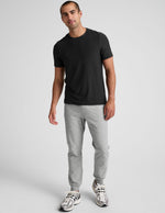 A man wears the light gray marled Spacedye Freefit Men's Zipper Pockets Jogger featuring a slim fit and tapered cuffed hems.