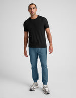 Man wearing Blue Spacedye™ Freefit Men's Jogger with banded cuffs, paired with a black t-shirt and silver sneakers.